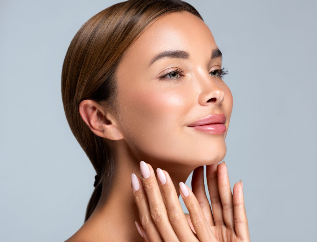 young woman touching face looking upward and smiling after dermal fillers
